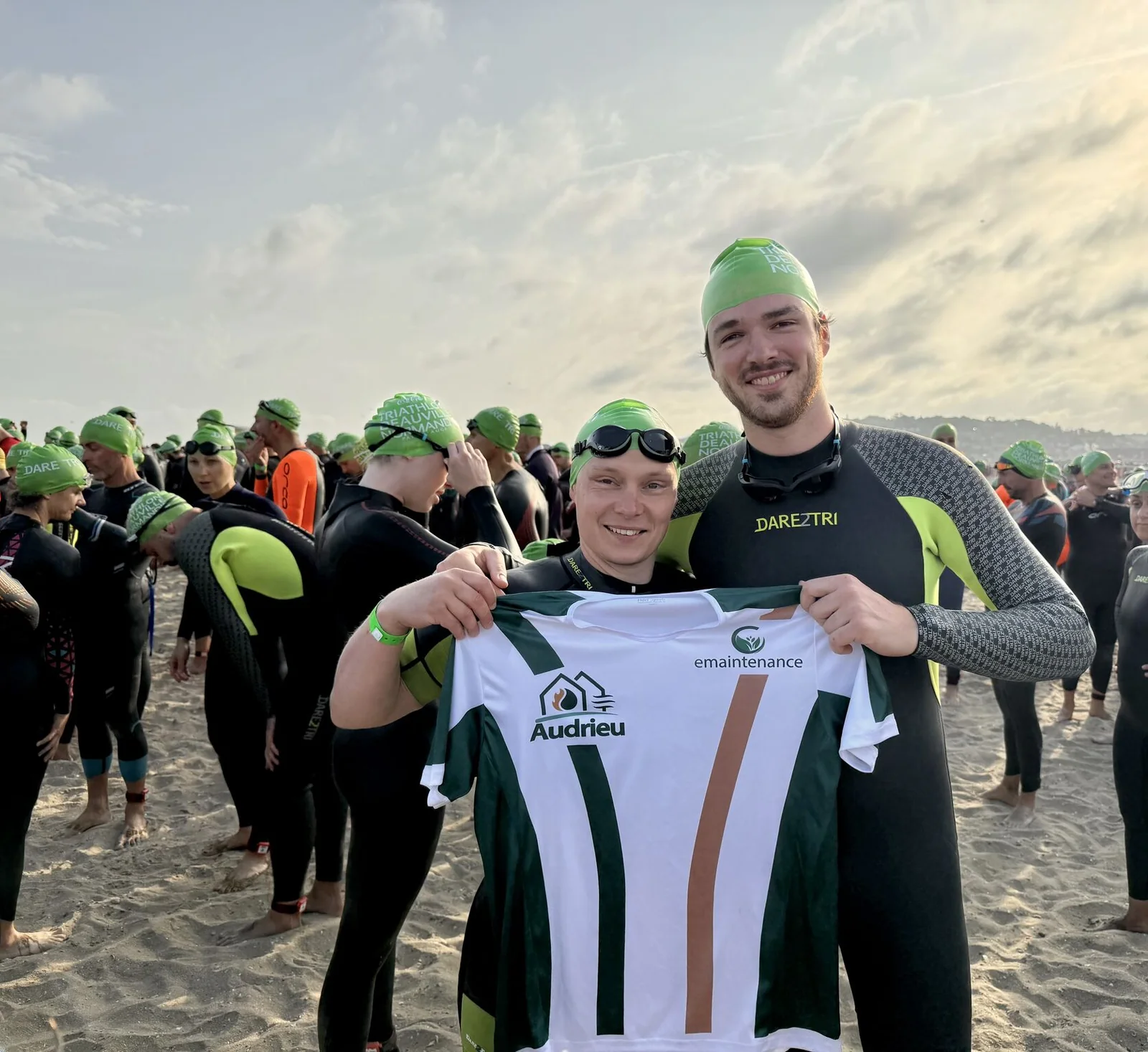 Deux participants brandissent le maillot Audrieu et E-maintenance avant l&rsquo;épreuve de natation