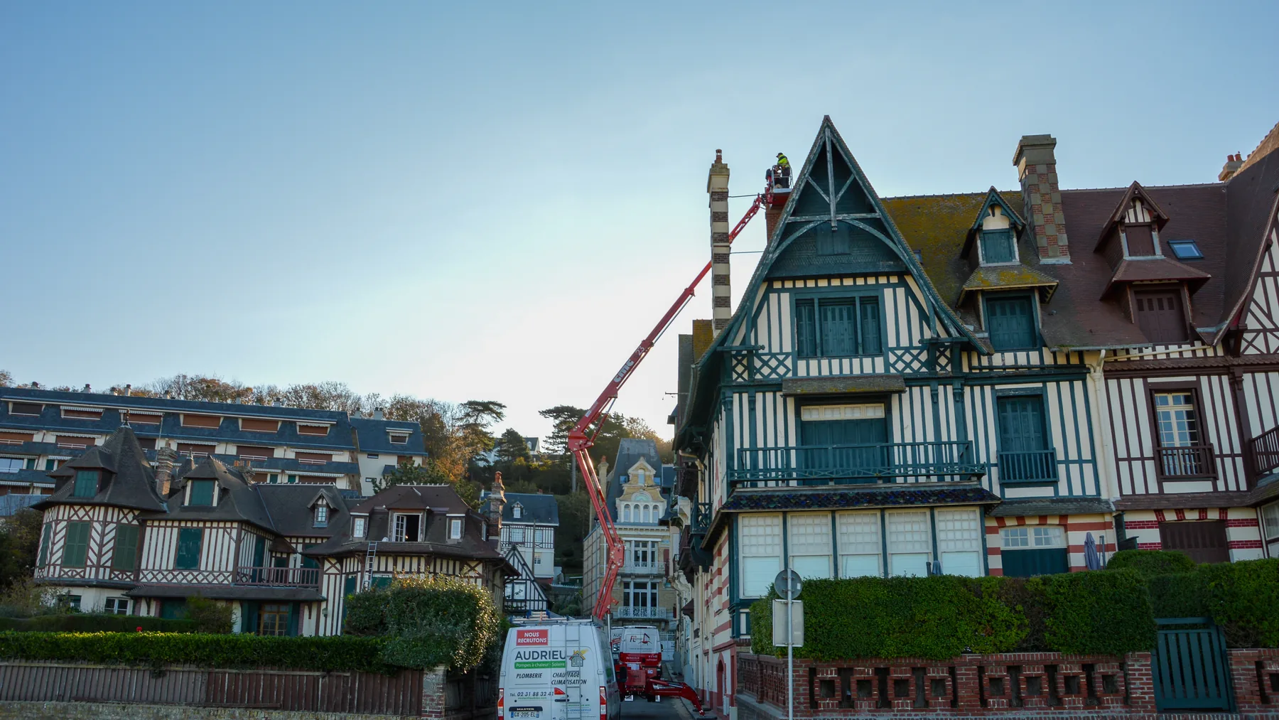 Grue déployée devant une villa normande à colombages