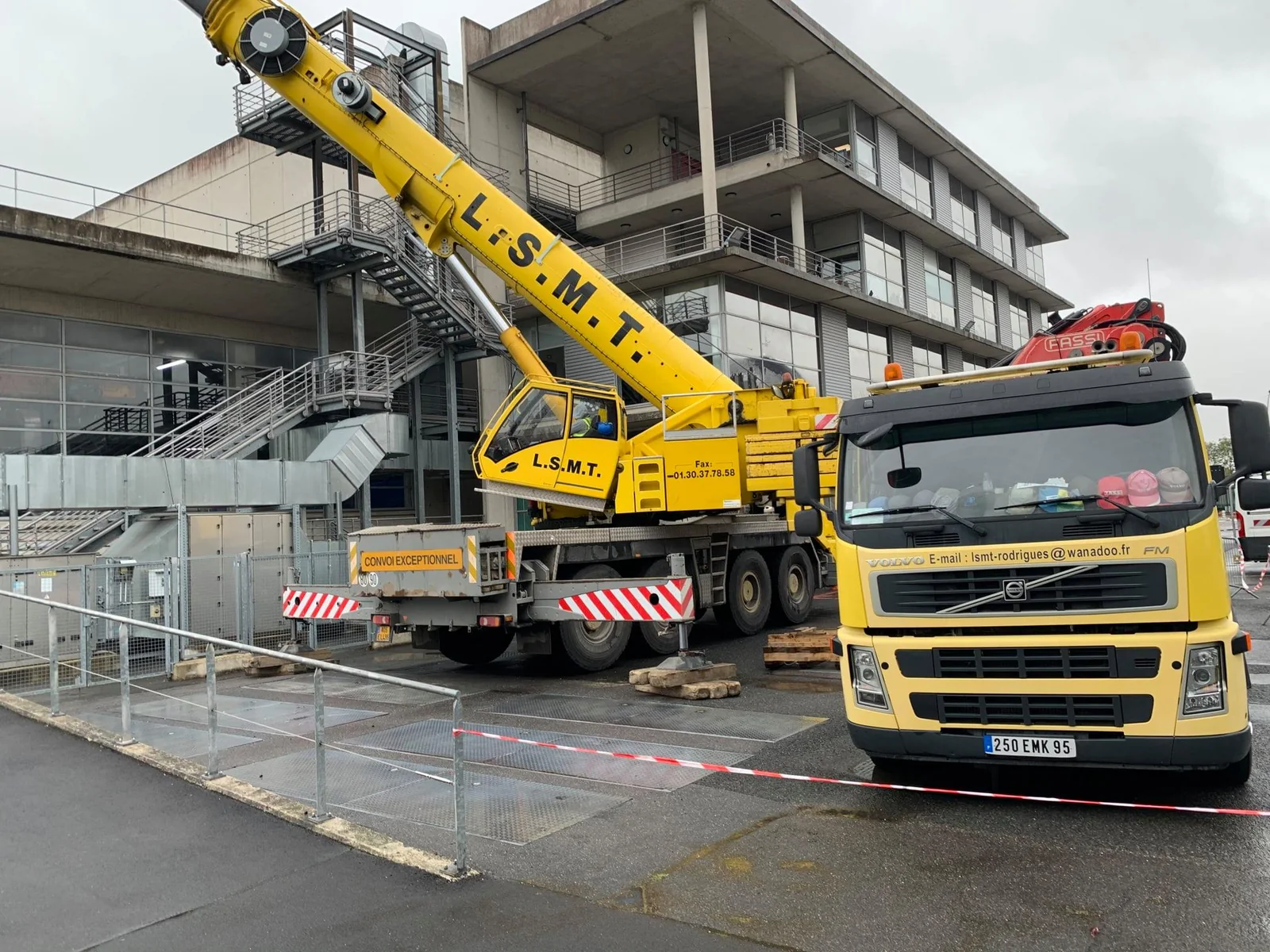 Camion-grue LSMT déployé devant un bâtiment pour un échange de moteur