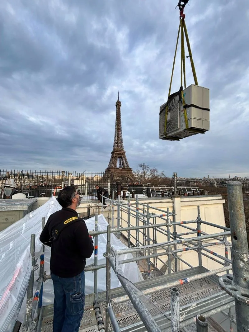 Pose d'un groupe de climatisation sur un toit parisien face à la tour Eiffel